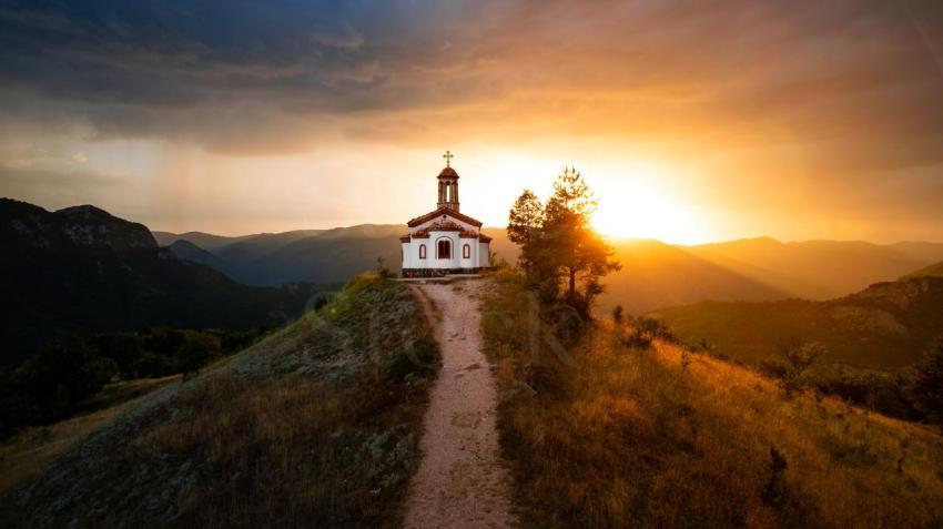 small chapel on top of a hill during sunset