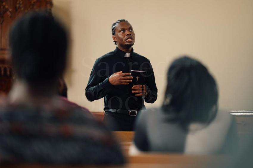 Young priest delivering sermon holding holy bible