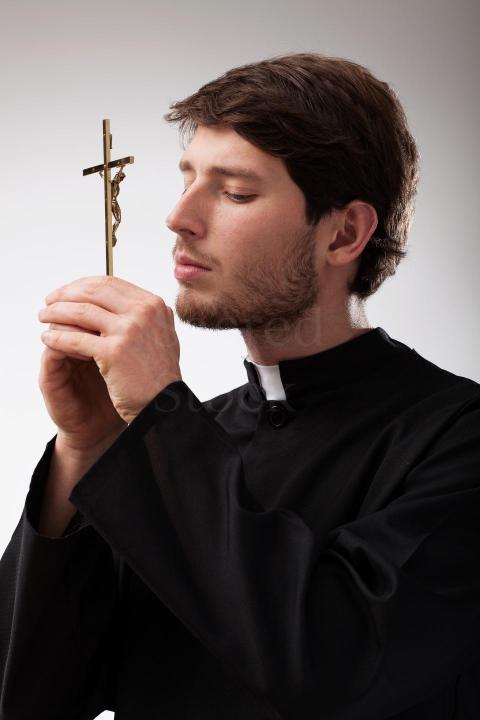 youn christian priest is praying to cross